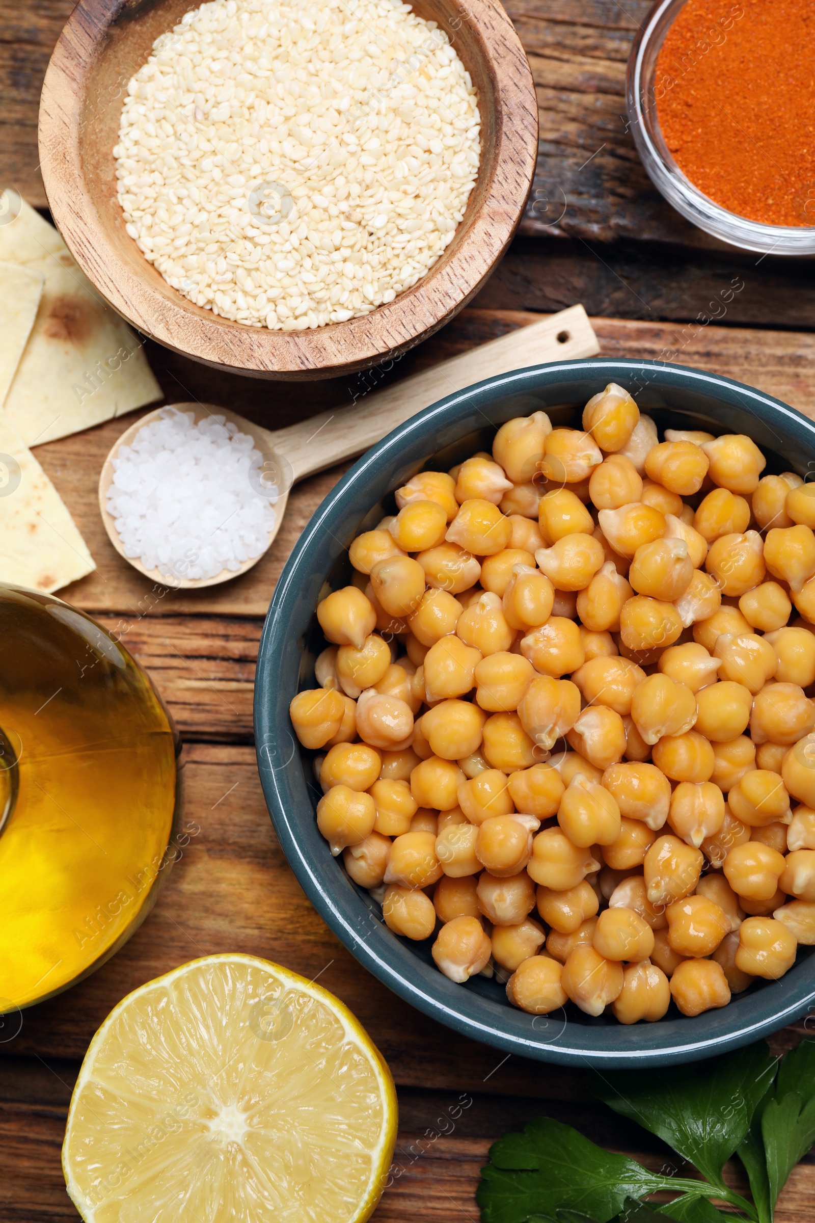 Photo of Delicious chickpeas and different ingredients on wooden table, flat lay. Cooking hummus