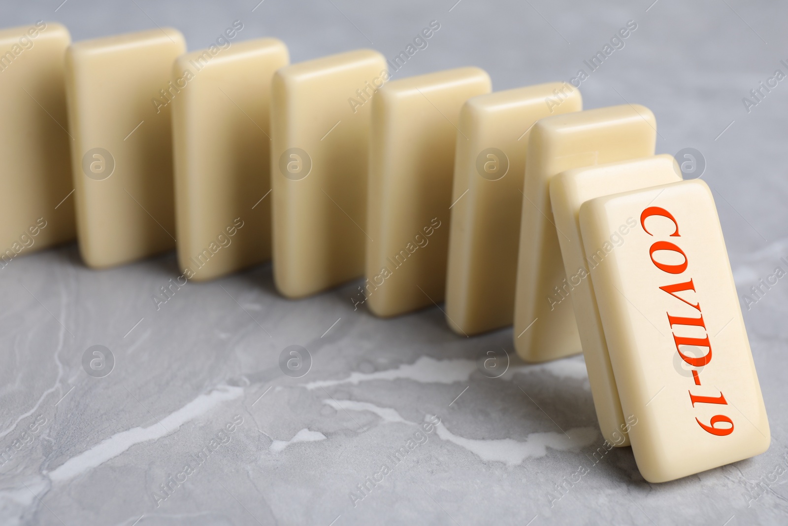 Photo of Falling domino tiles on grey marble table, closeup. Spreading of coronavirus concept