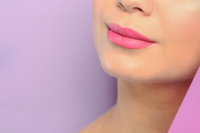 Young woman wearing beautiful lipstick on color background, closeup. Space for text