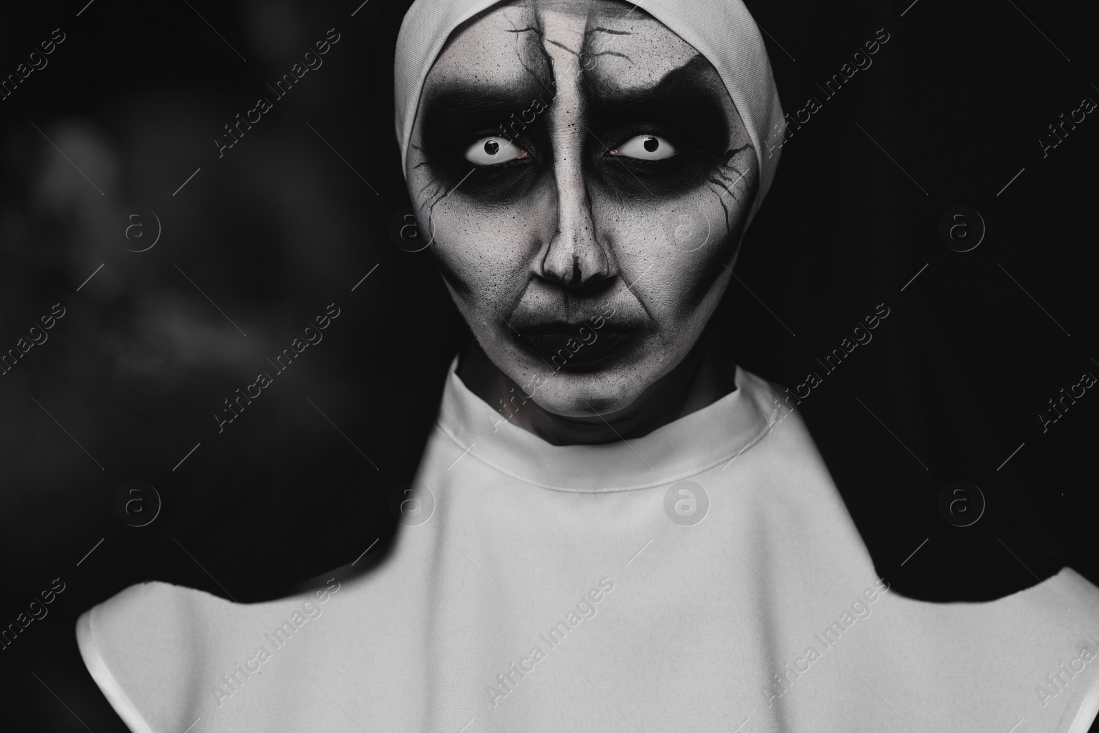 Photo of Portrait of scary devilish nun on black background. Halloween party look