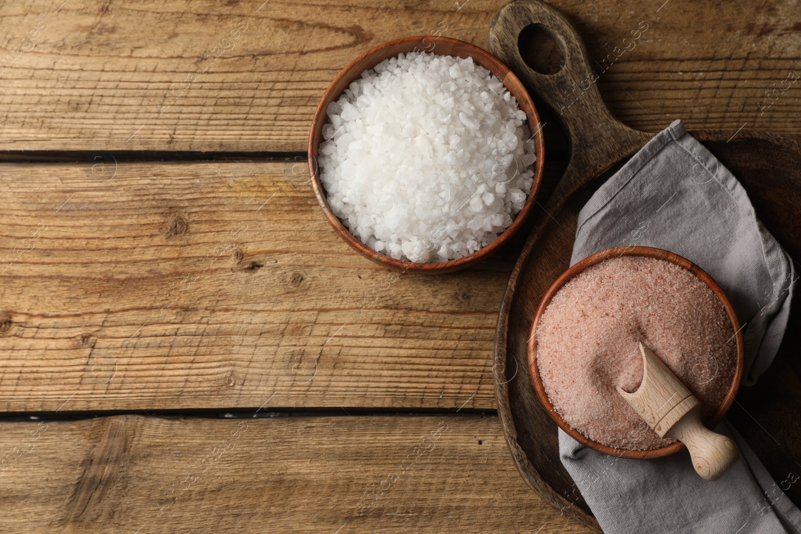 Photo of Different natural salt on wooden table, flat lay. Space for text