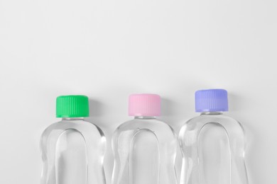 Photo of Transparent bottles with baby oil on white background, flat lay. Space for text