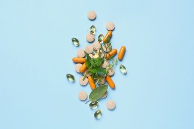 Different pills and herbs on light blue background, flat lay. Dietary supplements