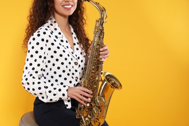 African American woman with saxophone on yellow background, closeup. Space for text