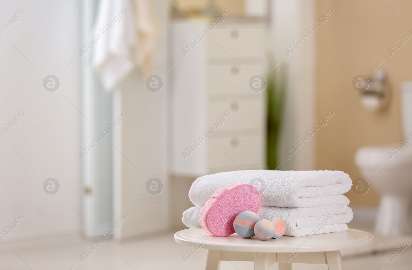 Photo of Clean towels and toiletries on table against blurred background