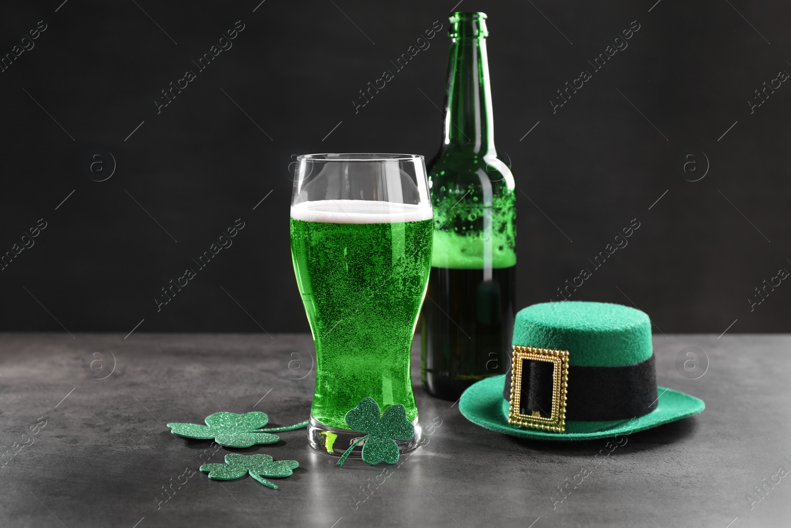 Photo of St. Patrick's day celebration. Green beer, leprechaun hat and decorative clover leaves on grey table