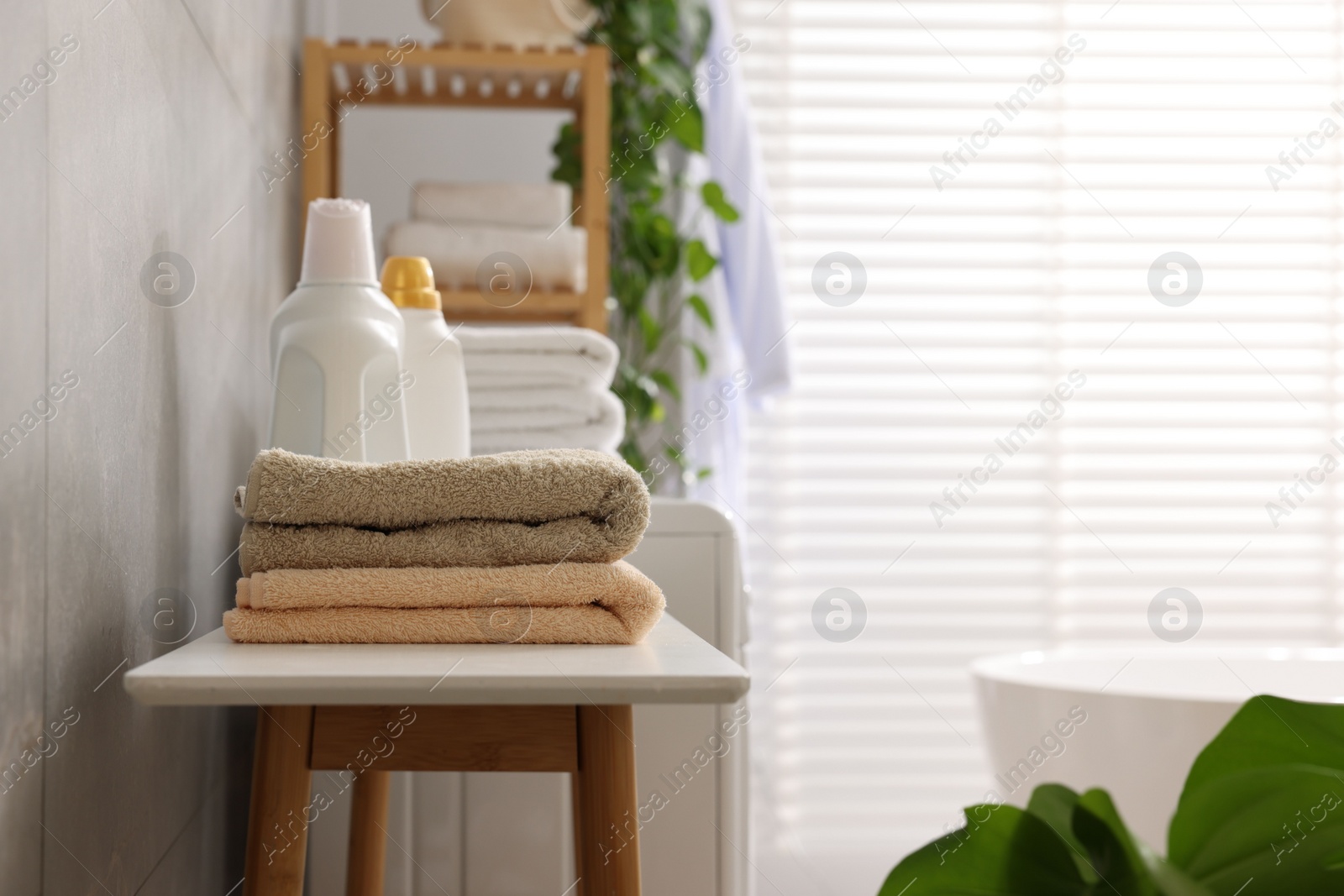 Photo of Soft towels and detergents on bench indoors. Space for text