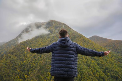 Photo of Man enjoying picturesque mountain landscape, back view