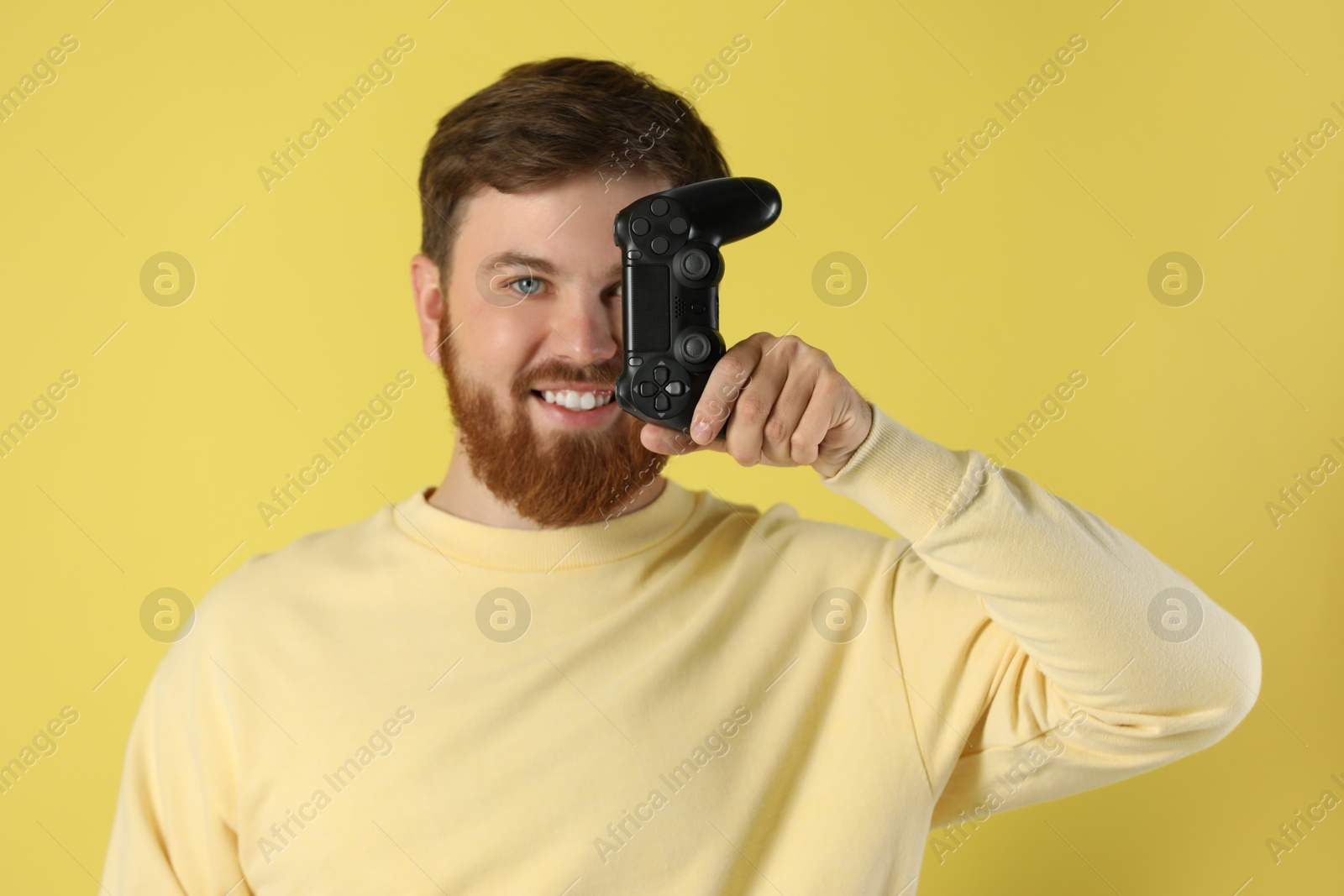 Photo of Smiling man with game controller on pale yellow background