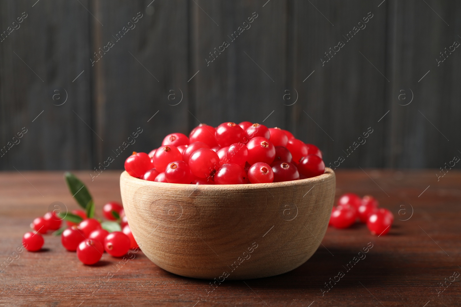 Photo of Tasty ripe cranberries on brown wooden table, closeup