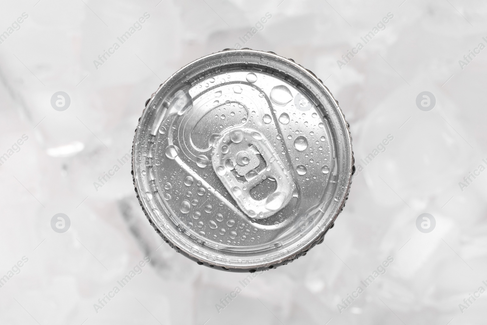 Photo of Energy drink in wet can on light background, top view