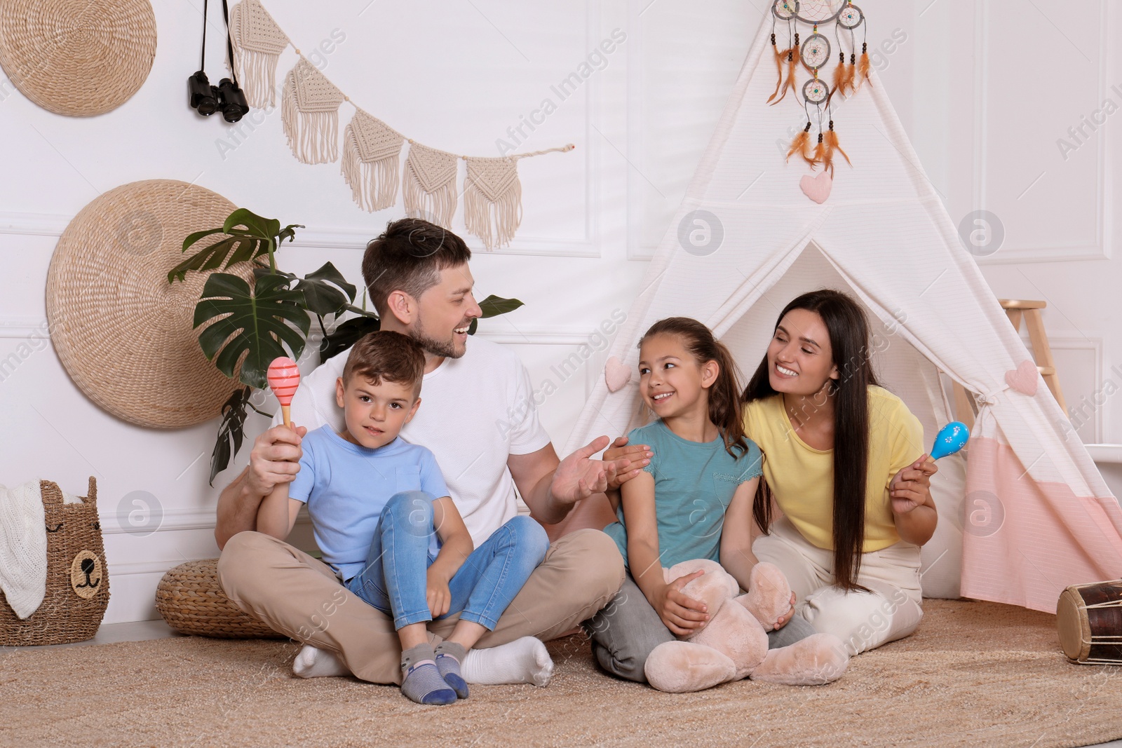 Photo of Happy family spending time together near toy wigwam at home