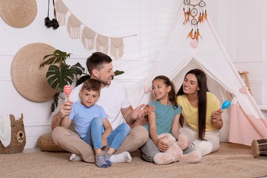 Photo of Happy family spending time together near toy wigwam at home