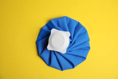 Ice pack on yellow background, top view