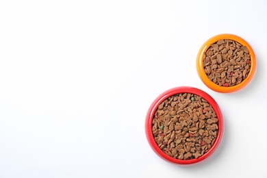 Bowls of dry pet food on white background, top view