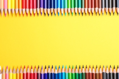 Photo of Flat lay composition with color pencils on yellow background. Space for text
