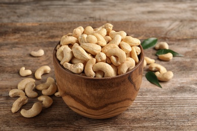 Tasty cashew nuts in bowl on wooden table