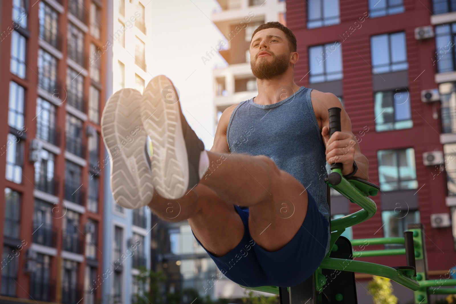 Photo of Man doing leg rise exercise at outdoor gym, low angle view