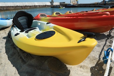 Photo of Many colorful kayaks on sand near sea, closeup