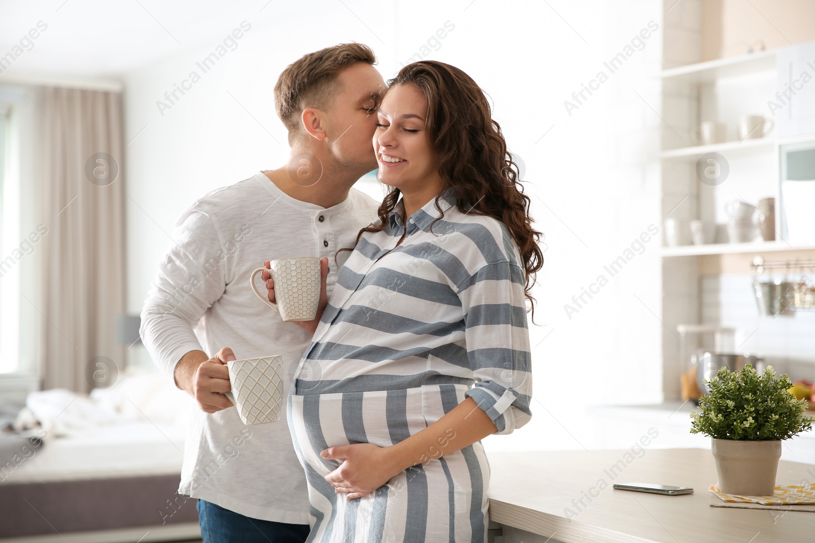 Photo of Pregnant woman with her husband in kitchen. Happy young family