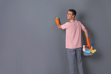 Man in gloves cleaning grey wall with sponge