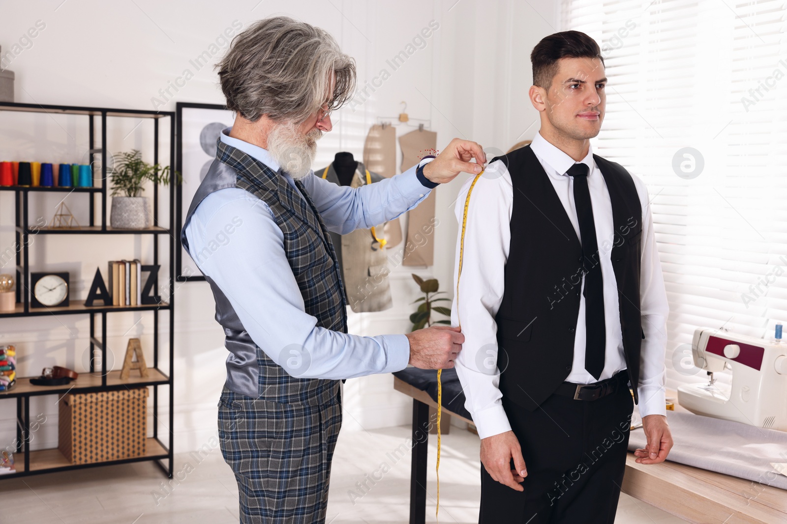 Photo of Professional tailor measuring shirt sleeve length in atelier