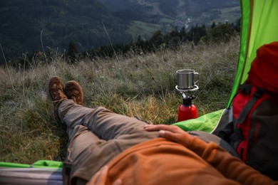 Photo of Man resting inside of camping tent in mountains, closeup