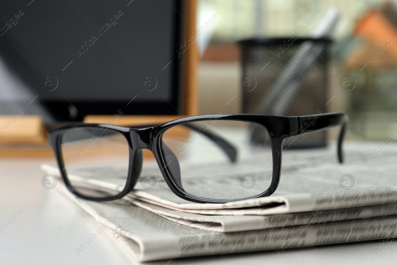 Photo of Stack of newspapers and glasses on white table indoors, closeup