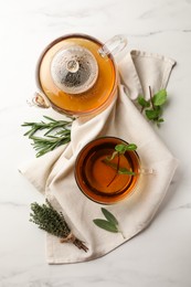 Photo of Aromatic herbal tea with rosemary, sage, thyme and mint on white marble table, flat lay