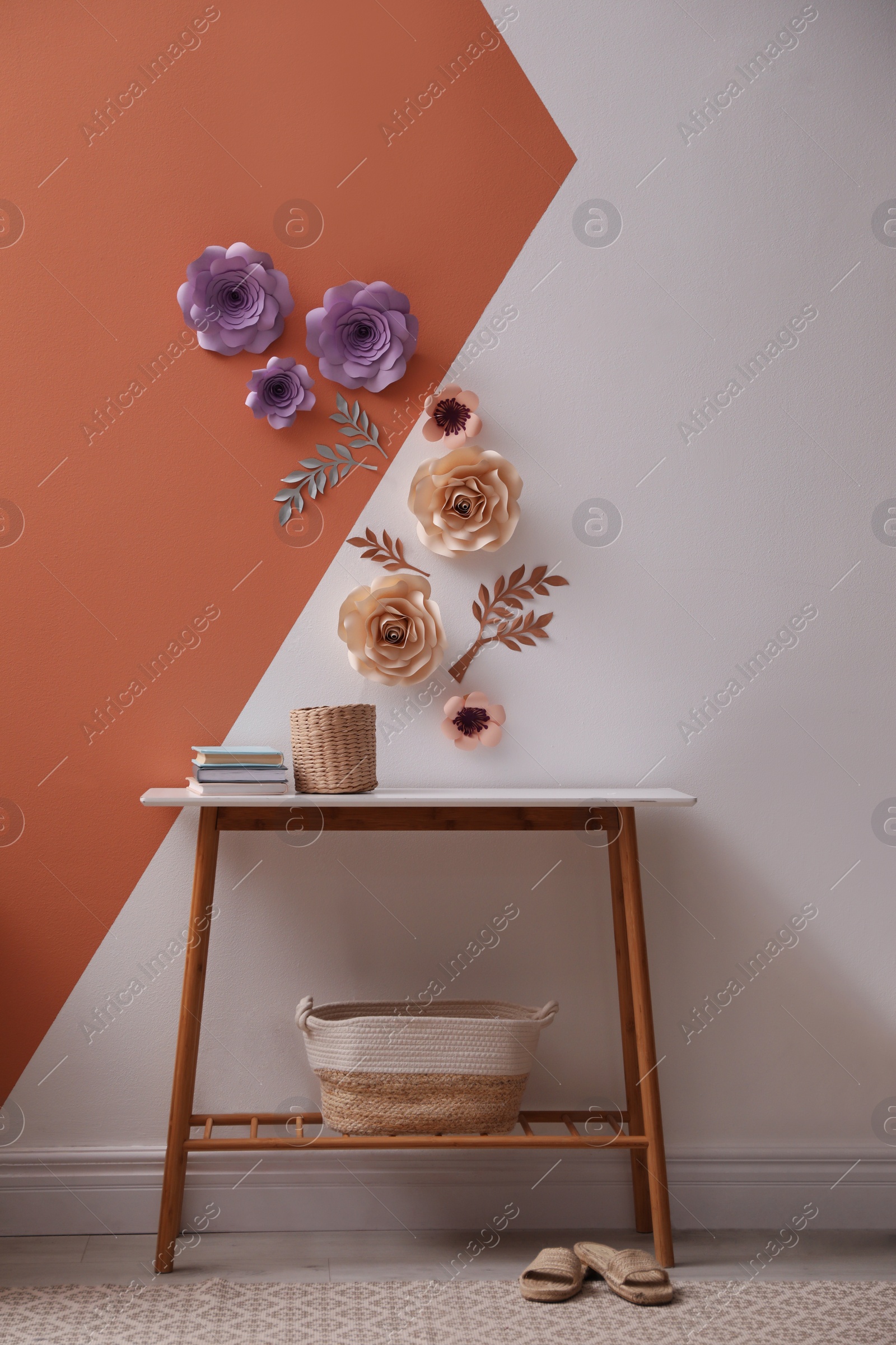 Photo of Books and holder on table near color wall with floral decor indoors