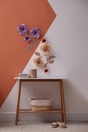 Photo of Books and holder on table near color wall with floral decor indoors
