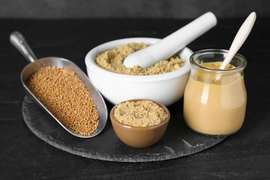 Photo of Aromatic mustard powder and seeds on black table