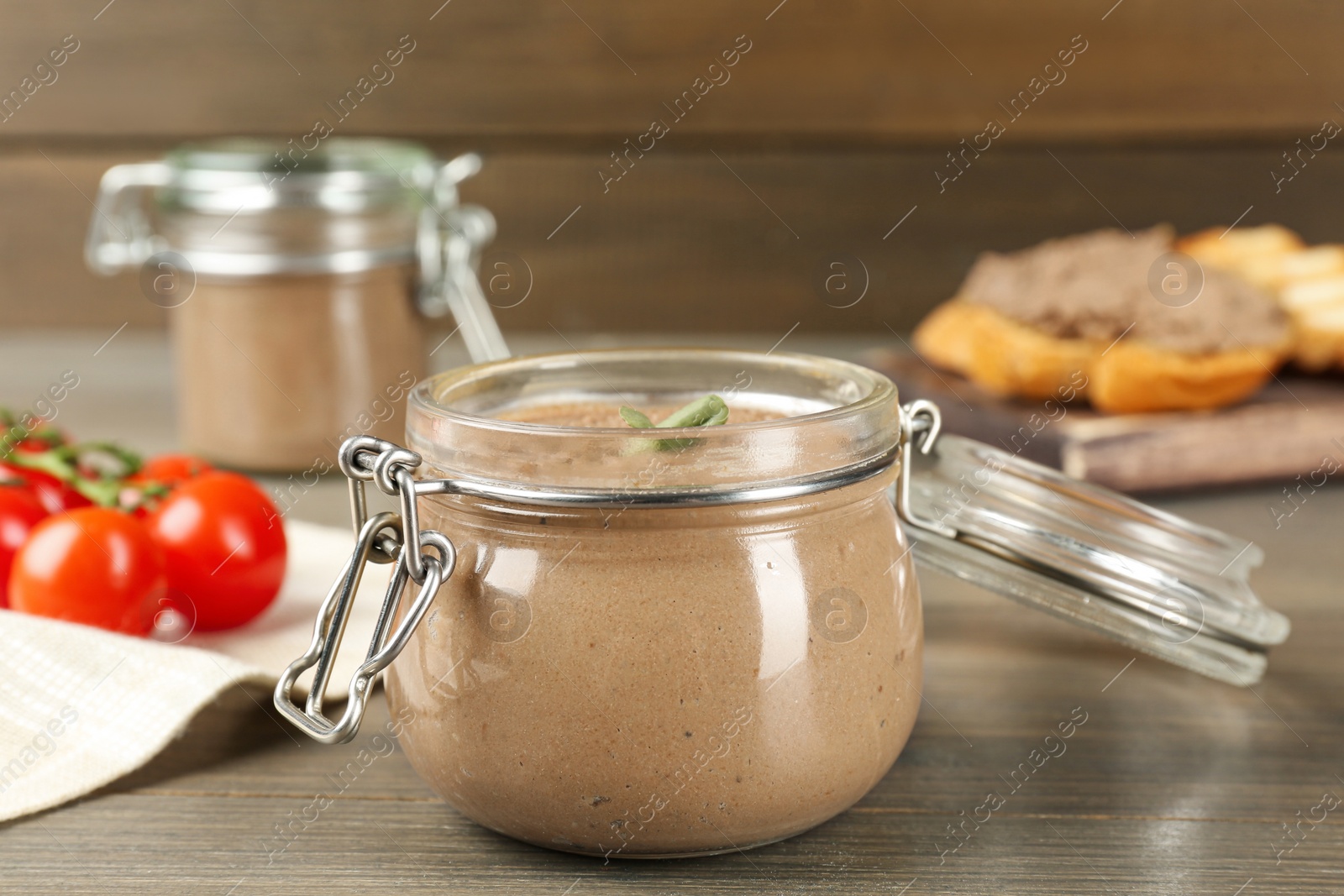 Photo of Glass jar with delicious liver pate on wooden table, closeup