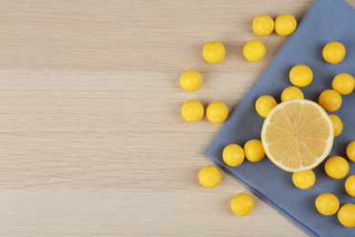 Flat lay composition with tasty lemon drops on wooden table. Space for text