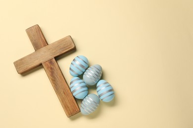 Photo of Wooden cross and painted Easter eggs on beige background, flat lay. Space for text