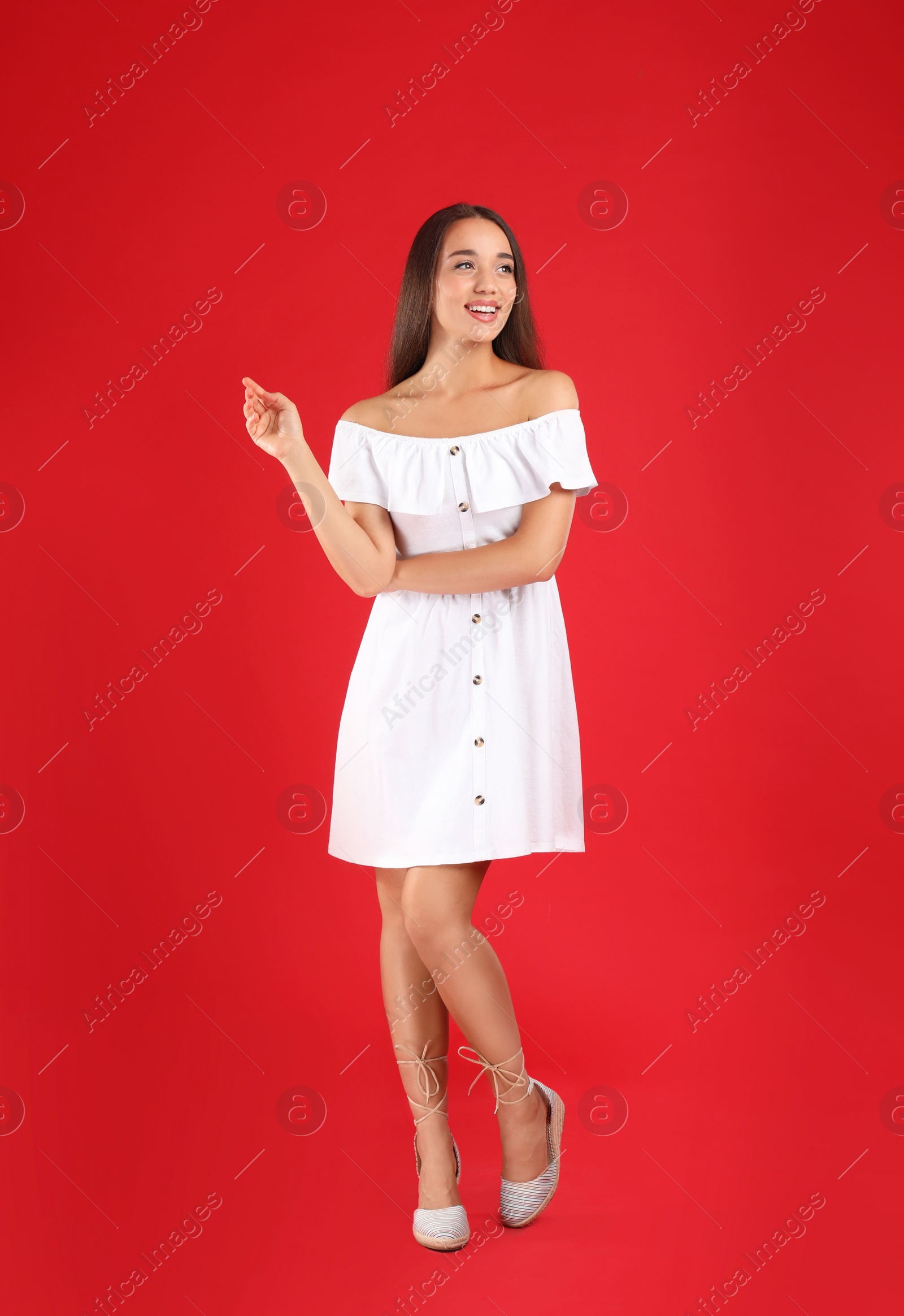 Photo of Young woman wearing stylish white dress on red background