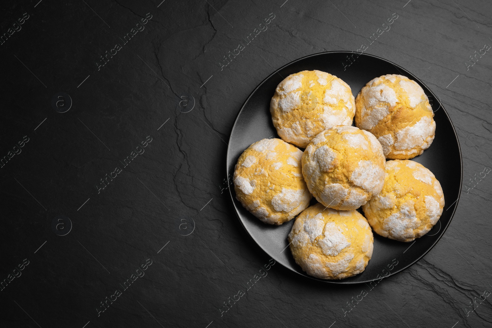 Photo of Plate with delicious lemon cookies on black table, top view. Space for text