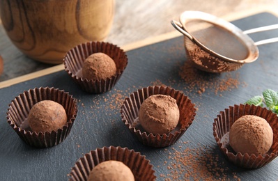 Tasty chocolate truffles on board, closeup view