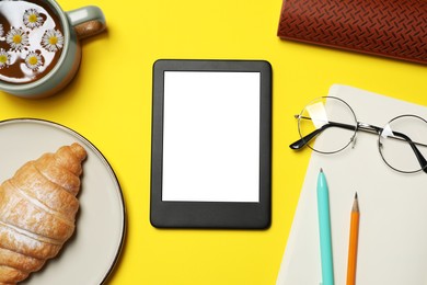 Flat lay composition with modern e-book reader on yellow background