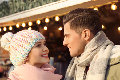 Photo of Happy couple in warm clothes at winter fair. Christmas season