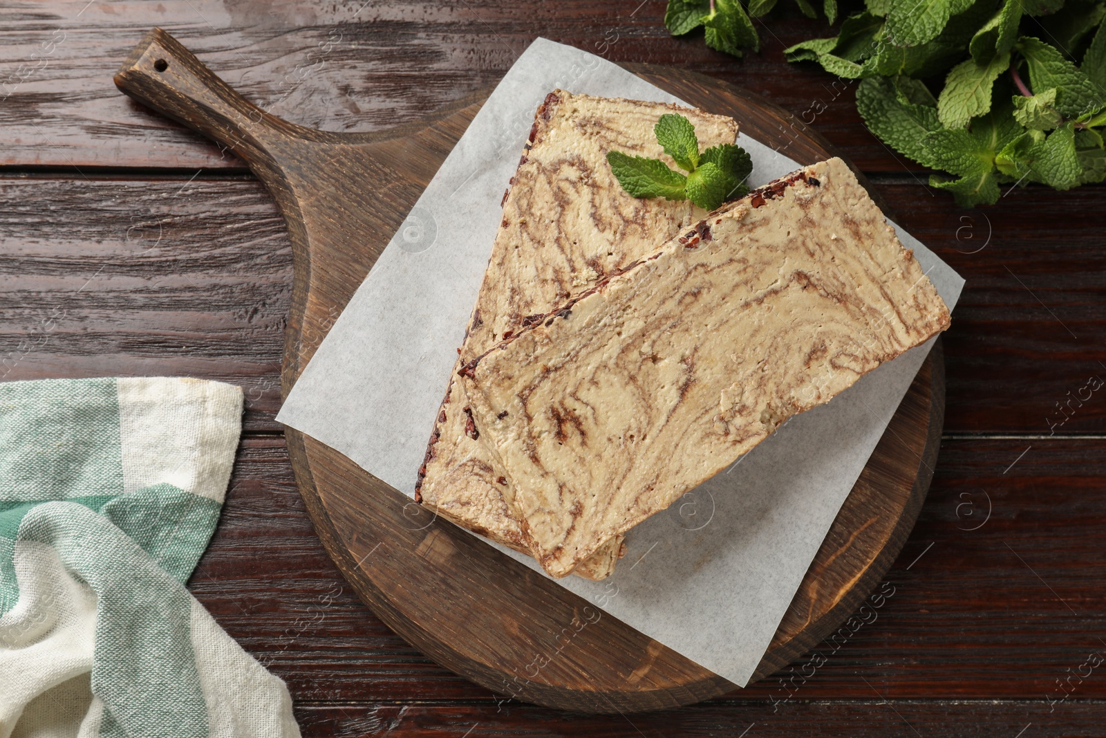 Photo of Pieces of tasty chocolate halva with mint on wooden table, top view