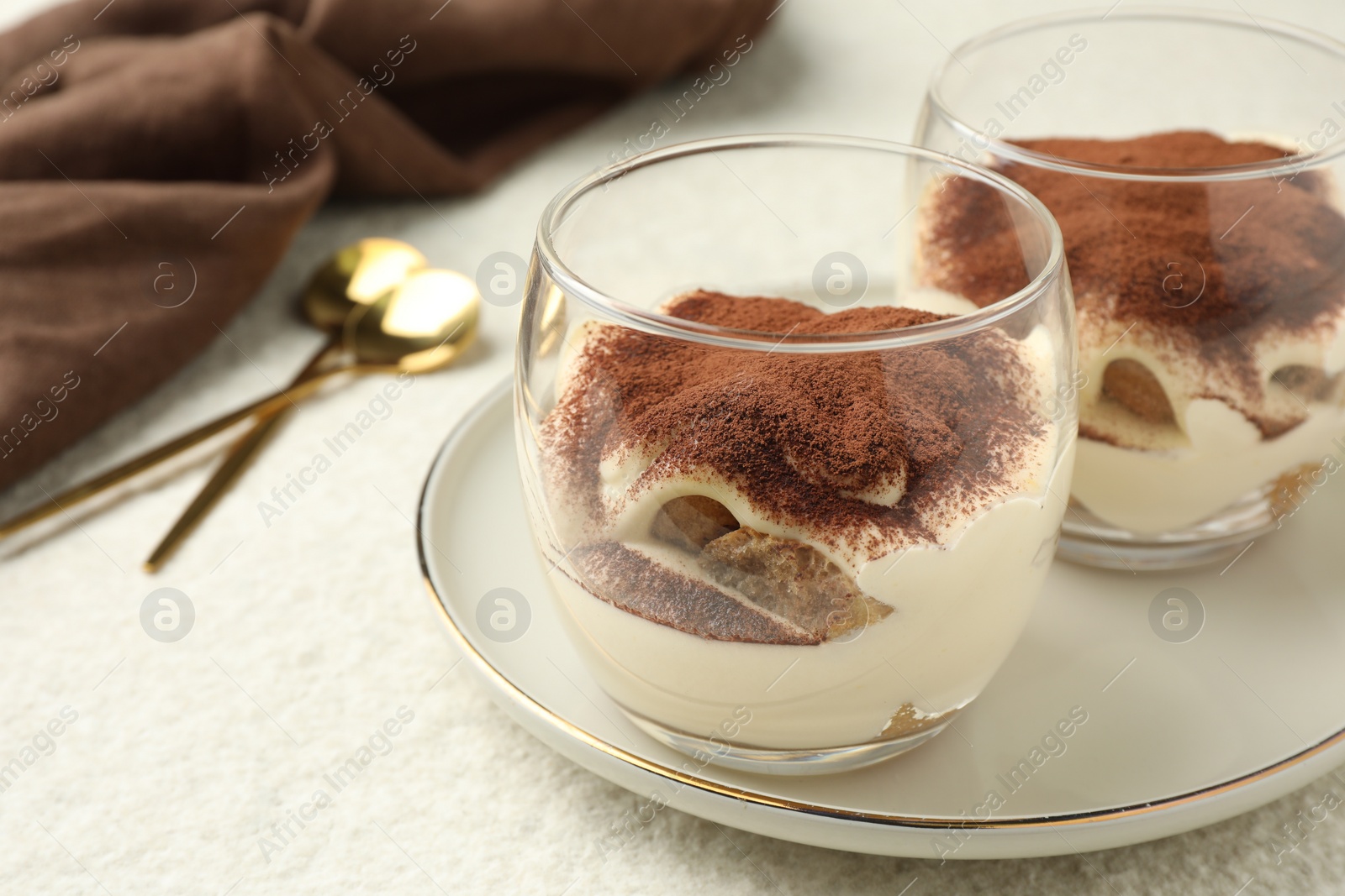 Photo of Delicious tiramisu in glasses on white table, closeup. Space for text