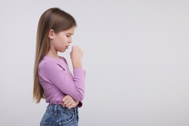 Sick girl coughing on light background, space for text