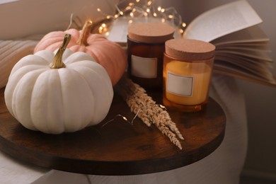 Wooden board with beautiful pumpkins and candles indoors