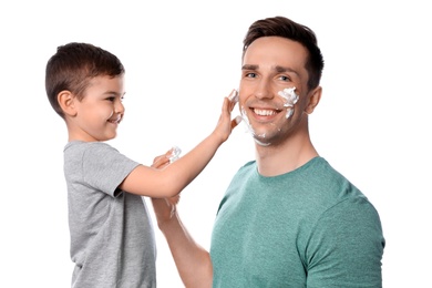 Dad and his little son applying shaving foam against white background