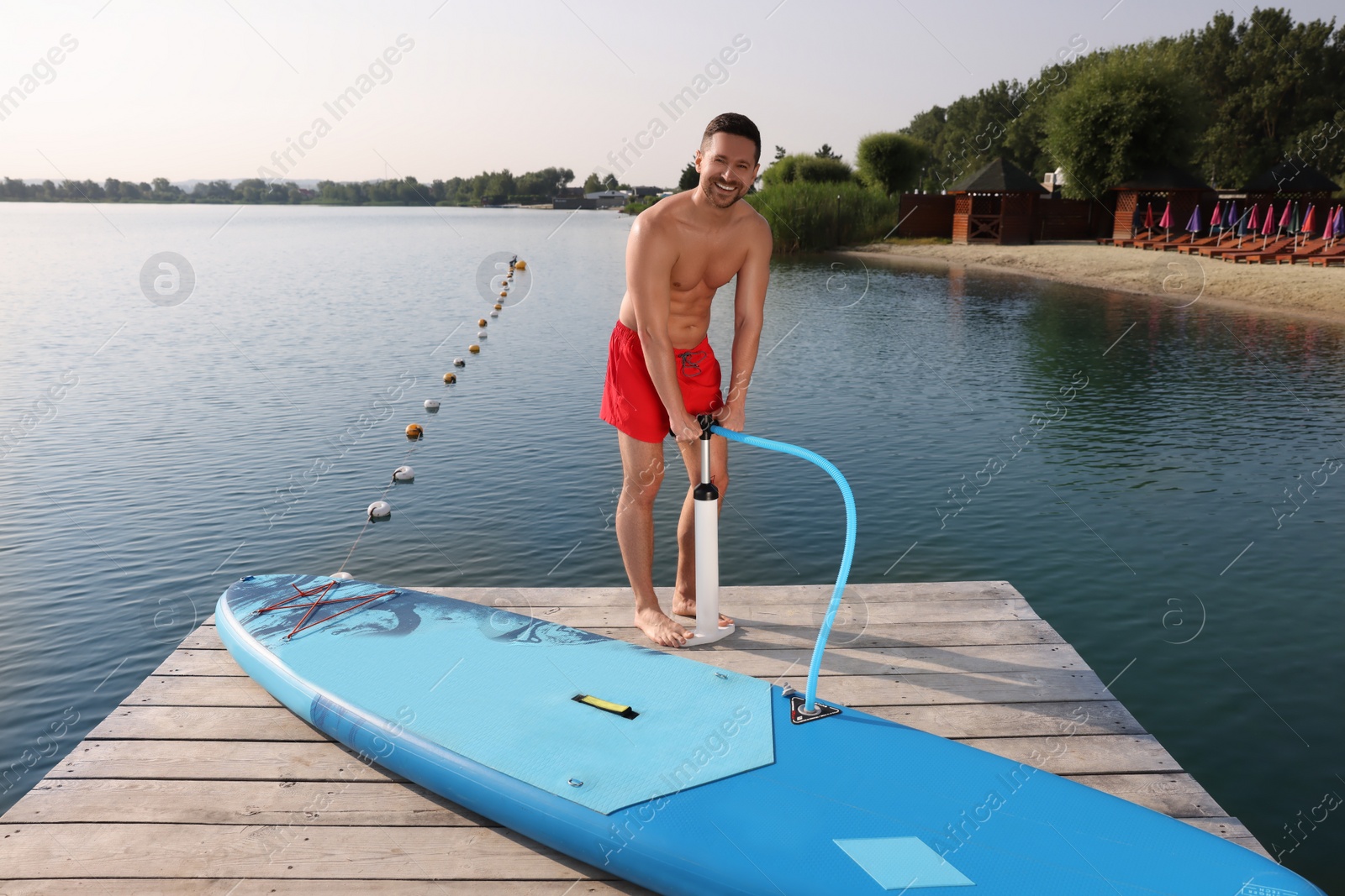 Photo of Man pumping up SUP board on pier