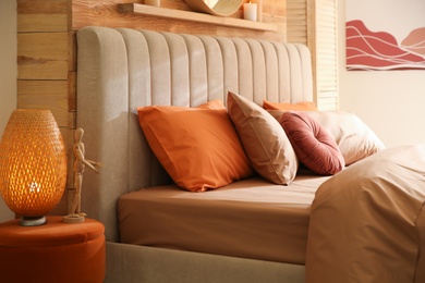 Photo of Bed with brown linens in cozy bedroom. Interior design