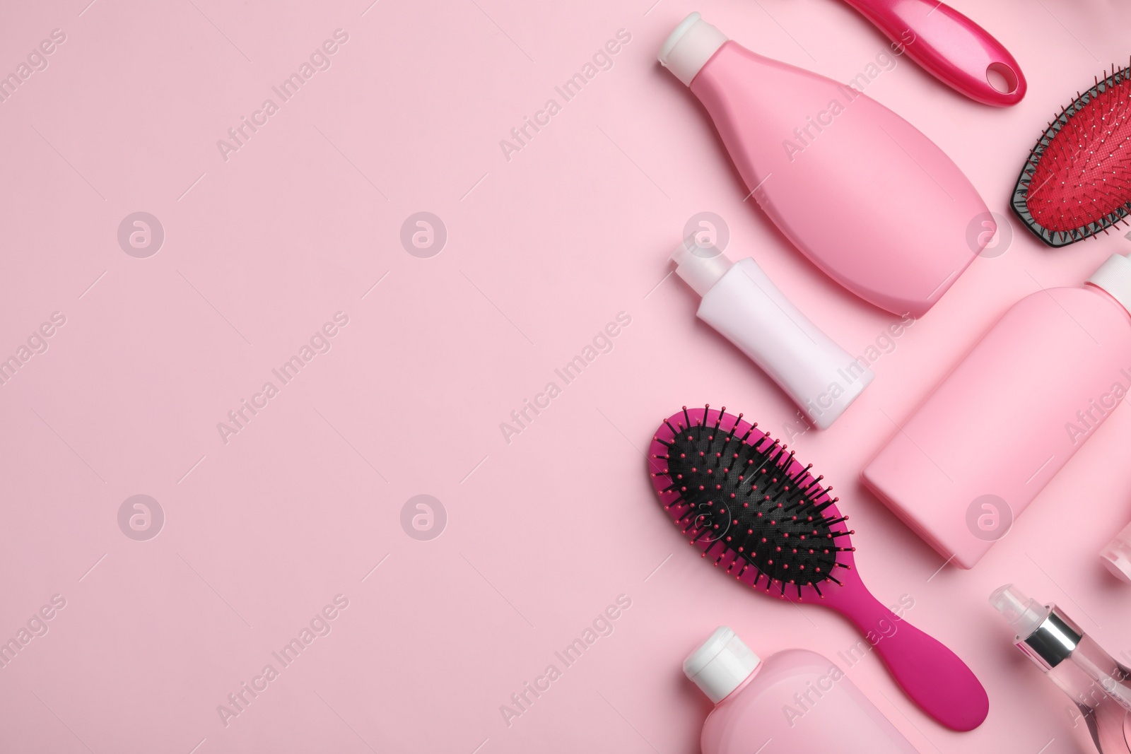 Photo of Flat lay composition with hair cosmetic products and tools on pink background. Space for text