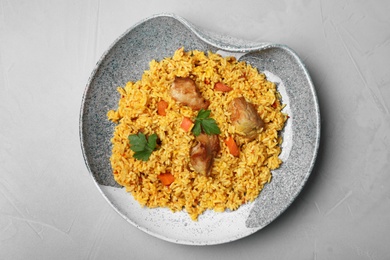 Photo of Plate with delicious rice pilaf on grey background, top view