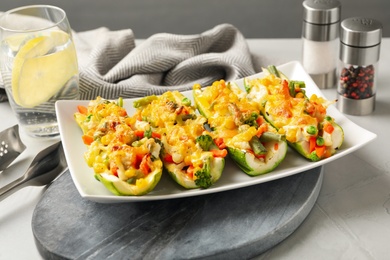 Photo of Baked stuffed zucchinis on light table, closeup